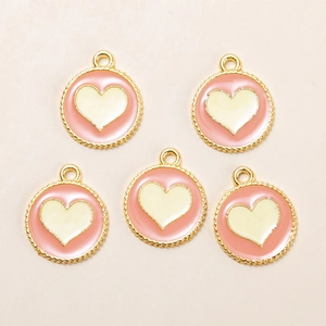Macro shot of five pink and white heart pendants with golden scalloped edges for DIY jewelry