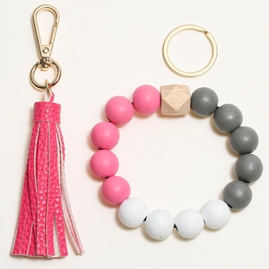 Detail of wooden beaded bracelet keychain with pink leather tassel and gold lobster clasp