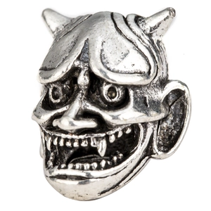 Macro shot of a vintage silver Viking bead featuring a detailed demon mask design