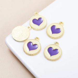 Macro shot of cream heart pendants with purple enamel and gold-plated serrated edges