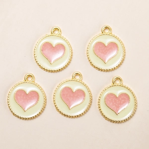 Detailed view of five gold heart-shaped pendants with pink enamel on a minimalist surface