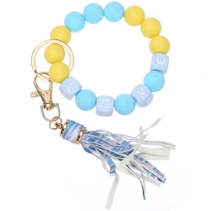 Detail of yellow and blue silicone bead bracelet with LOVE cubes and a striped tassel charm