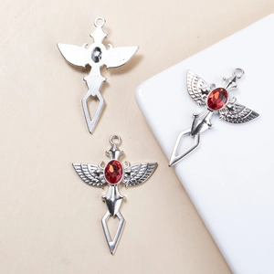 Détail du pendentif croix épée vintage avec pierre rouge et gravures d'ailes argent