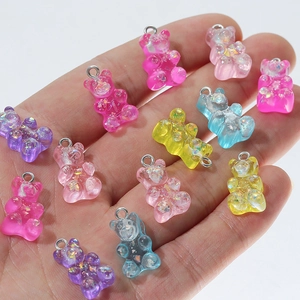 Close-up of assorted resin gummy bear charms with glitter filling held in palm