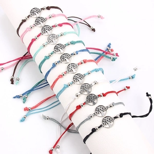 Detail van 12 kleurrijke gevlochten armbanden met levensboom op een witte display