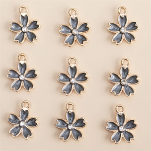 Lot de neuf breloques fleurs dorées avec émail gris et cristal central pour bijoux DIY
