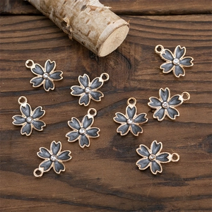 Détail macro de breloques fleurs en émail gris avec cristaux sur surface bois