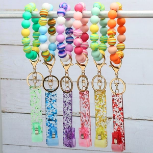 Assorted colorful silicone bead wristlet keychains with clips and acrylic tags on wood