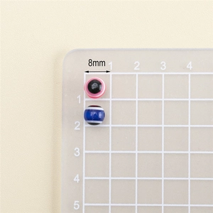 Close-up of 8mm resin evil eye beads and striped charms for DIY jewelry making
