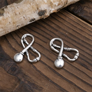 Macro detail of vintage silver stethoscope charms for DIY jewelry on a rustic wood background