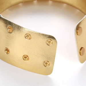 Detail van gouden lederen choker met metaaltextuur en metalen drukknoopsluiting
