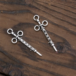 Detailed close-up of retro silver syringe pendants with skull design on wood background
