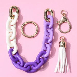 Cadena de acrílico morada y blanca con borla blanca y anillo dorado sobre fondo rosado