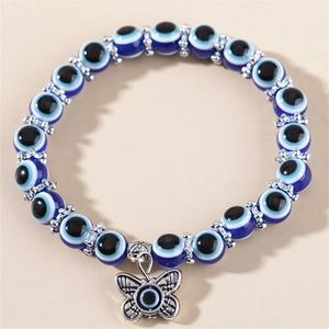 Détail macro d'un bracelet en résine mauvais œil bleu avec un pendentif papillon argenté