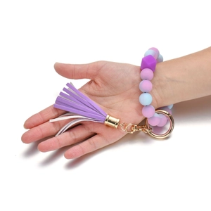 Bracciale portachiavi in perline di silicone con nappa viola e anello dorato sulla mano