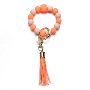 Dettaglio del portachiavi da polso in silicone arancione con anello d'oro e nappa in PU