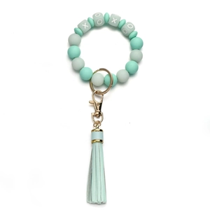 Detailed macro view of mint green silicone beads with XOXO square accents and a silk tassel