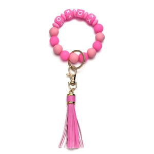 Close-up of pink silicone beaded wristlet keychain with XO pattern and leather tassel