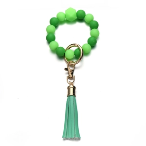 Dettaglio del bracciale con perle di silicone verdi, gancio dorato e nappa in pelle