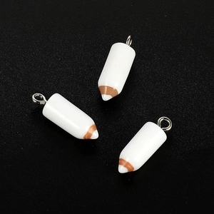 Detailed view of three white resin pencil charms with silver loops on black background