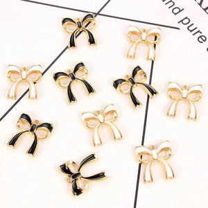 Macro shot of black and white enamel bow-tie alloy charms with gold frames for DIY jewelry