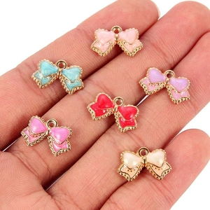Close-up of six colorful glitter bow pendants held in hand for DIY jewelry making