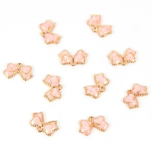 Macro detail of ten light pink enamel bow charms with marble texture and gold plating