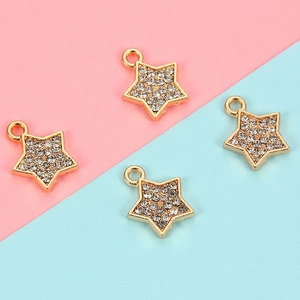 Detailed close-up of four gold alloy star pendants with rhinestones for DIY jewelry making
