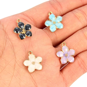 Colorful floral charms with gold edges held in hand to show size and enamel details
