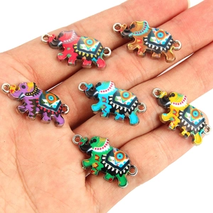 Colorful enamel elephant charm set with bohemian patterns shown in a hand for scale