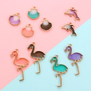Macro shot of colorful flamingo and shark alloy pendants with glitter drip oil finish