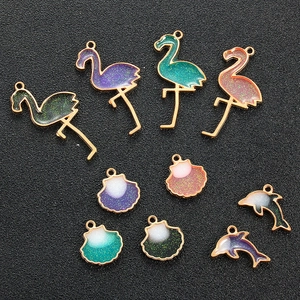 Macro view of gold-plated enamel alloy charms in flamingo, shell, and dolphin shapes