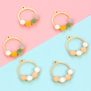 Detail of DIY jewelry charms with colorful enamel dots and gold metal ring frames