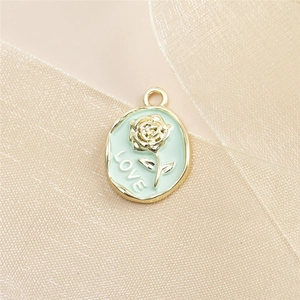 Macro detail of oval gold alloy rose pendant with mint green enamel and LOVE engraving