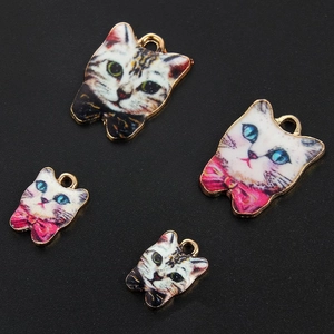 Detailed view of four enamel cat face pendants with gold trim for jewelry making