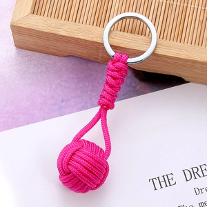 Macro detail of a hand-woven pink paracord monkey fist keychain with a polished silver ring