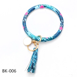 Detail of tropical floral PU leather ring keychain with gold clasp and matching tassel