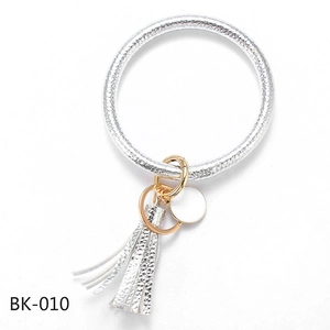 Detail of silver embossed PU leather wristlet keychain with gold ring and tassel charm