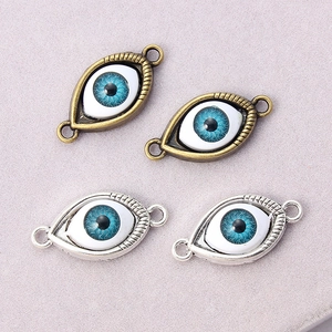 Detailed view of evil eye connector charms in antique bronze and silver for DIY jewelry