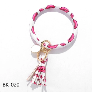 Detail of PU leather keychain bracelet with red lip pattern, tassel, and gold metal hardware