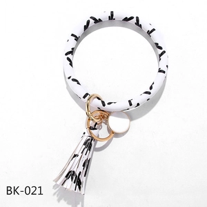 Detail of PU leather wristlet keychain with black ink pattern, tassel, and gold ring