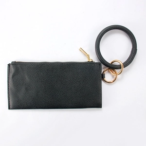 Detail view of black pebble leather clutch with gold zipper and round bracelet handle