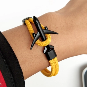 Détail d'un bracelet en paracorde jaune tressée avec fermoir noir mat en forme d'avion