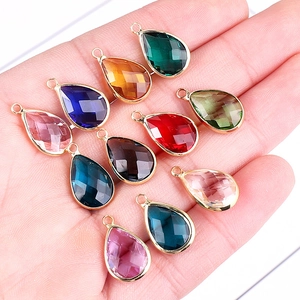 Multicolor faceted glass teardrop charms with gold-plated metal edges held in hand