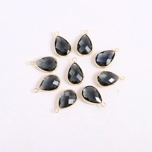 Radial layout of dark gray teardrop glass charms with gold metal edges for DIY jewelry
