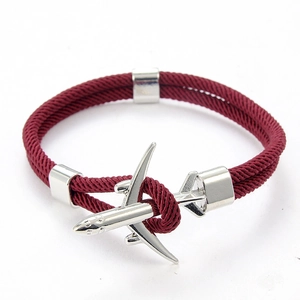 Détail du charm avion et du bracelet tressé rouge bordeaux avec accents argentés