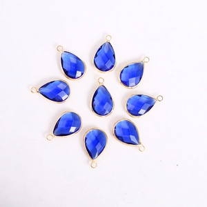 Macro detail of faceted dark blue glass teardrop charms with gold frames for DIY jewelry