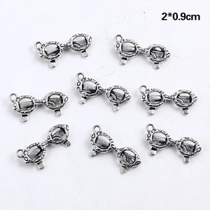 Détail macro de huit breloques lunettes argent antique pour bijoux DIY 2x0.9cm