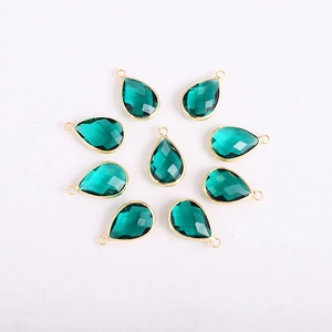 Detailed view of dark green faceted teardrop pendants with gold edges for DIY jewelry