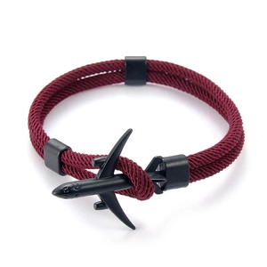 Détail d'un bracelet en paracorde rouge vin avec un charm d'avion en métal noir mat